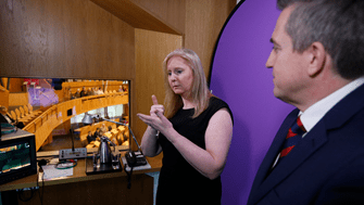Two British Sign Language interpreters carry out simultaneous translation for BSL users in a booth next to the Debating Chamber of the Scottish Parliament