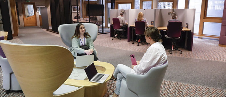 Two staff members having a meeting in a breakout area.